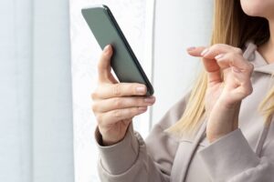 woman checking her phone- Big Texan Solar