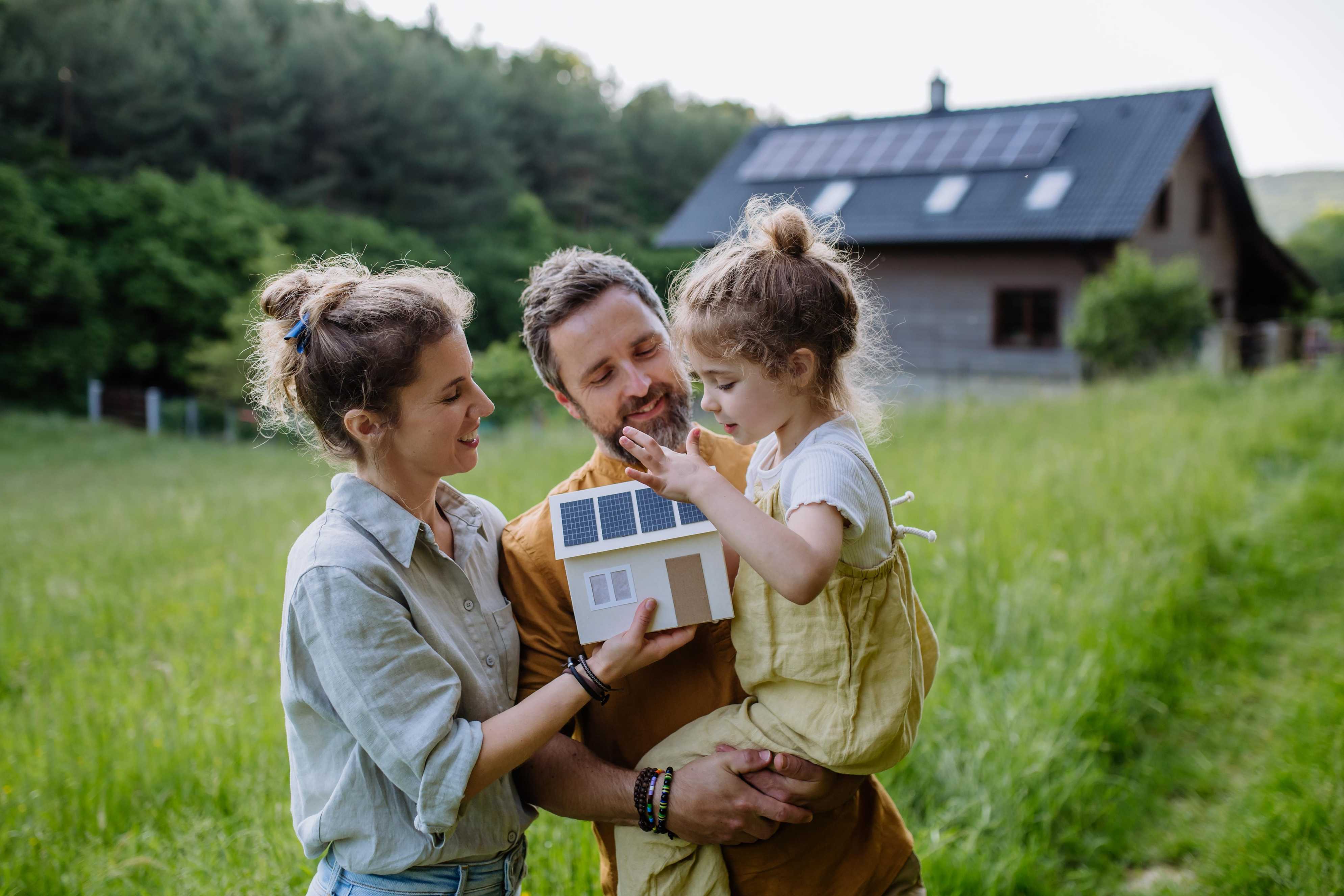 happy family infront of their house wtih newly installed solar panels