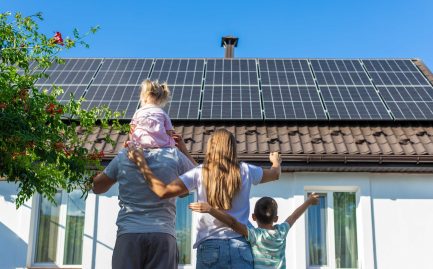 happy family looking at their house with newly installed solar panels