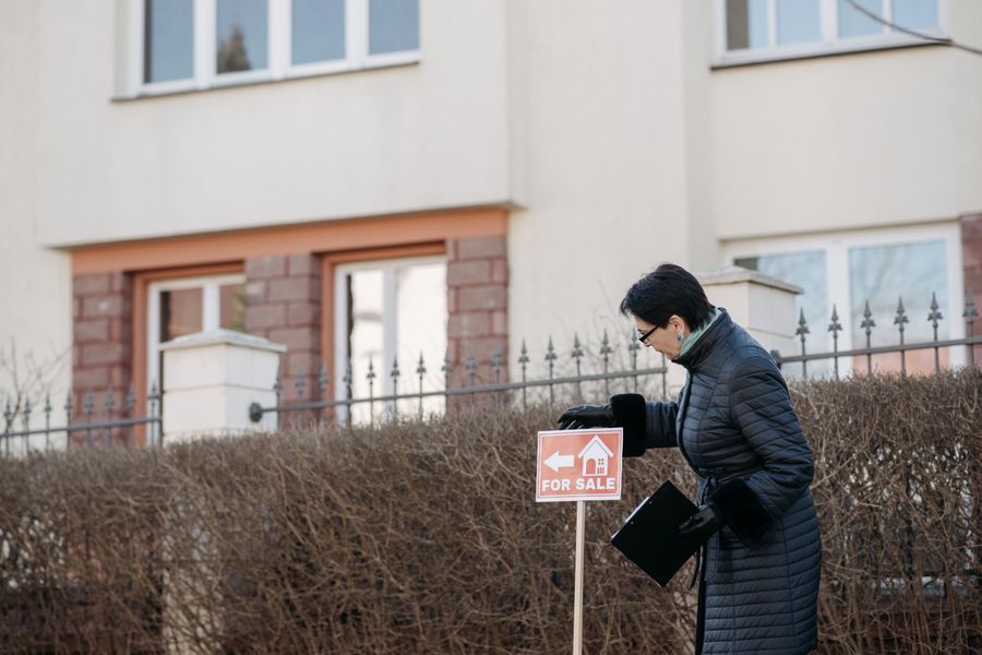 real estate agent placing a for sale sign outside a Texas solar home